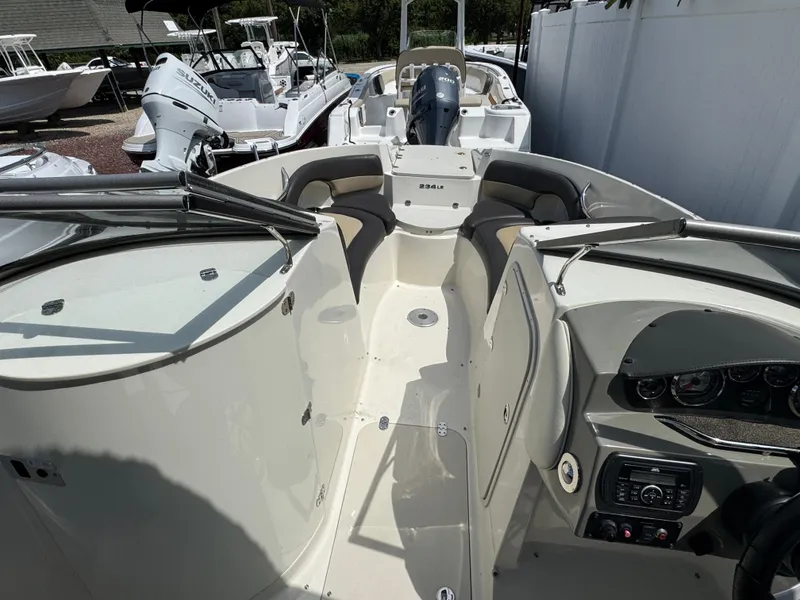 Slide: The Image of 2018 Stingray 234 LR boat interior with seating and control panel, docked among other boats. - 15