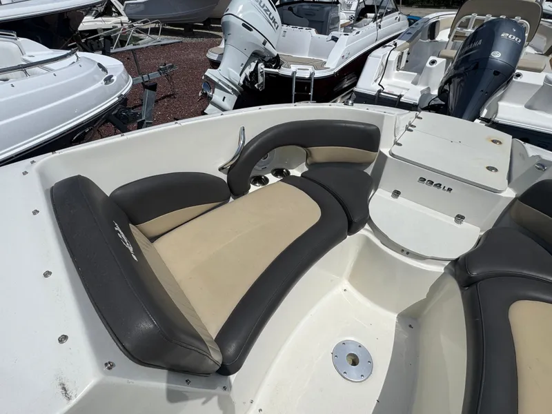 Slide: The Image of 2018 Stingray 234 LR boat interior with beige and black seating, surrounded by other boats. - 16