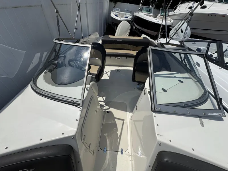Slide: The Image of 2018 Stingray 234 LR boat interior with seating and windshield, docked among other boats. - 24