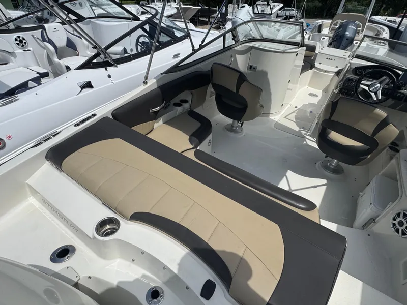 Slide: The Image of 2018 Stingray 234 LR boat interior with beige and black seating, steering wheel, and cup holders. - 3
