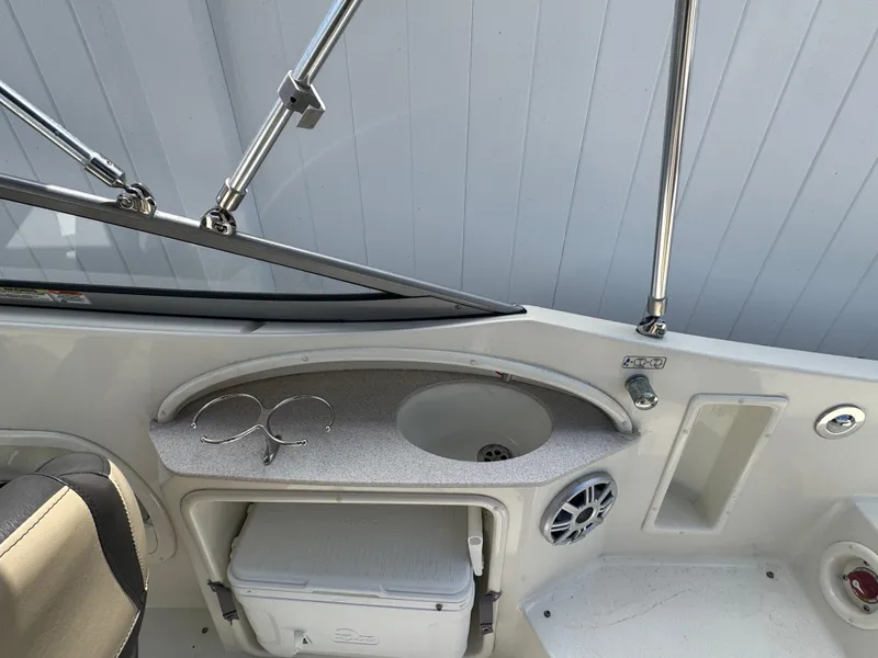 Slide: The Image of 2018 Stingray 234 LR boat interior with sink, cup holders, and storage compartment. - 6
