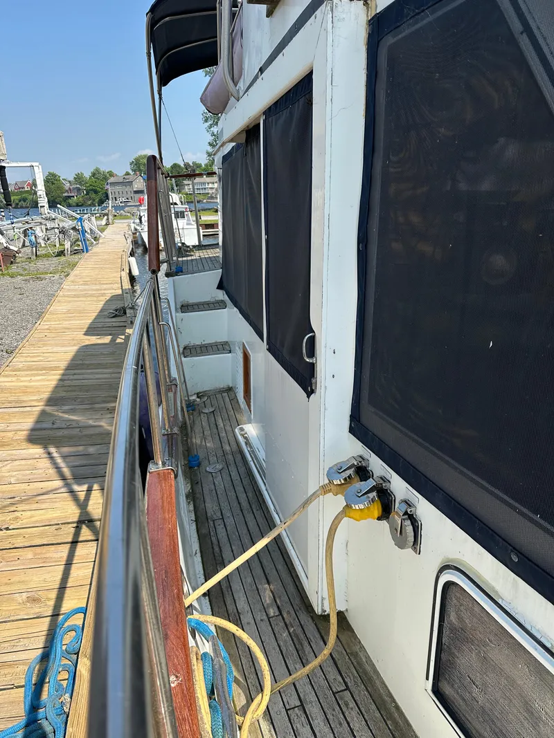 Slide: The Image of 1996 Island Gypsy 36 Aft Cabin yacht docked, showing side view with wooden deck and power connection. - 10