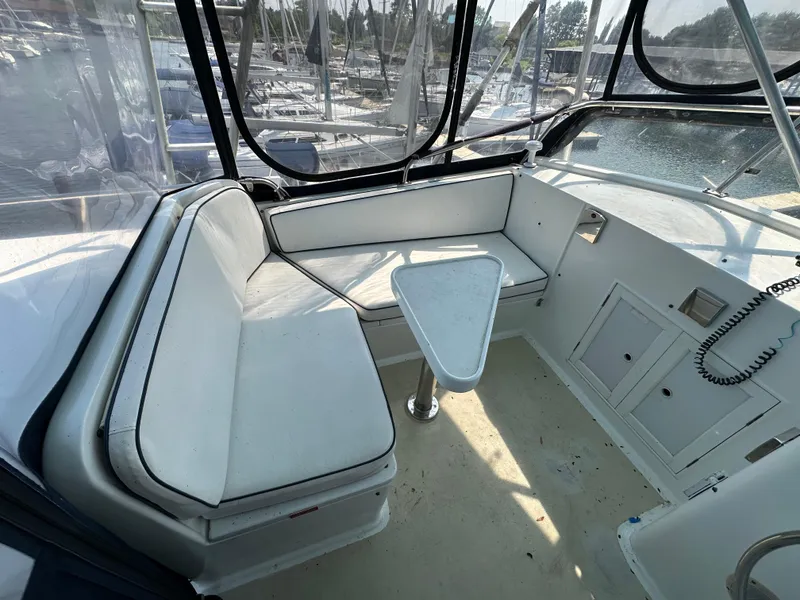 Slide: The Image of 1996 Island Gypsy 36 Aft Cabin interior with seating and triangular table, docked at marina. - 11