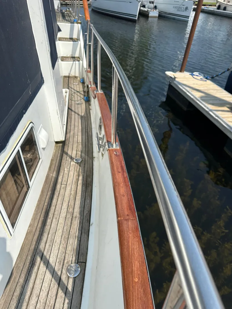 Slide: The Image of 1996 Island Gypsy 36 Aft Cabin yacht deck with wooden railings and marina view. - 15