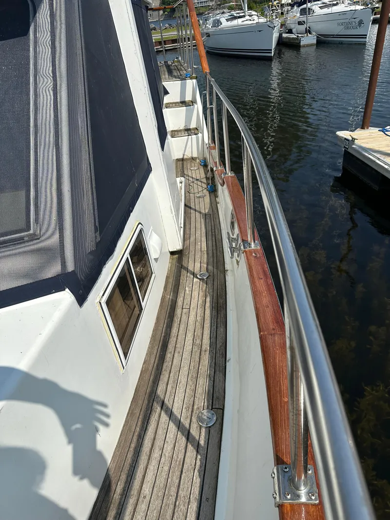 Slide: The Image of 1996 Island Gypsy 36 Aft Cabin yacht deck with wooden flooring and metal railings. - 16