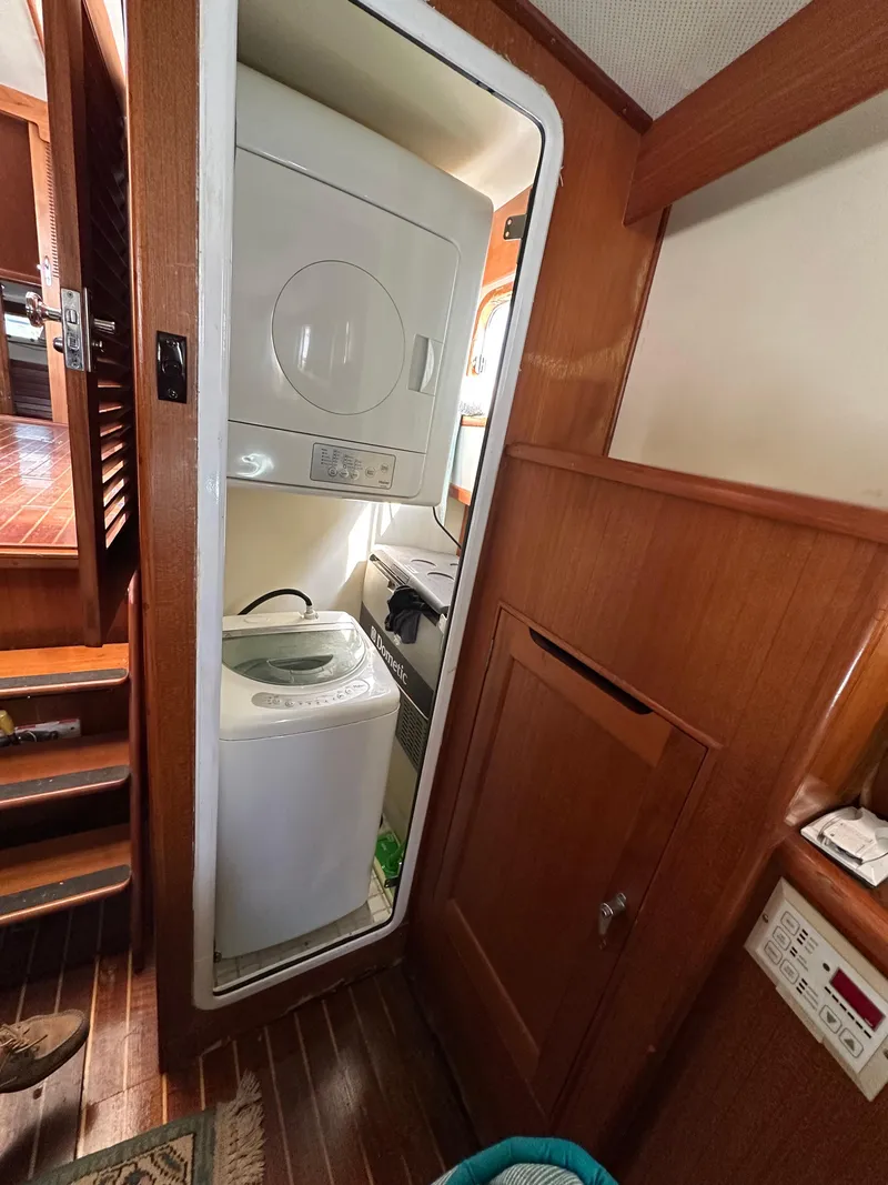 Slide: The Image of Laundry area inside 1996 Island Gypsy 36 Aft Cabin boat, featuring stacked washer and dryer. - 24