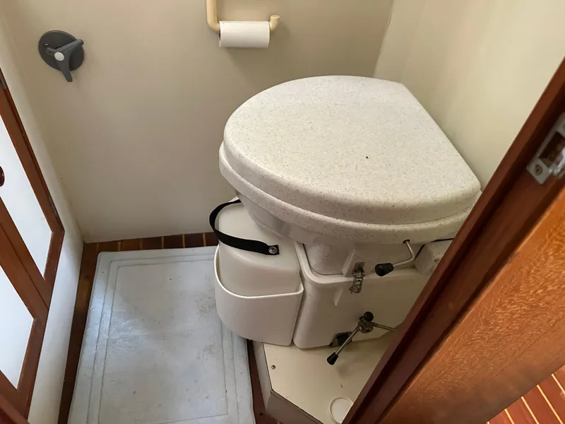 Slide: The Image of 1996 Island Gypsy 36 Aft Cabin bathroom with compact marine toilet and wooden flooring. - 25