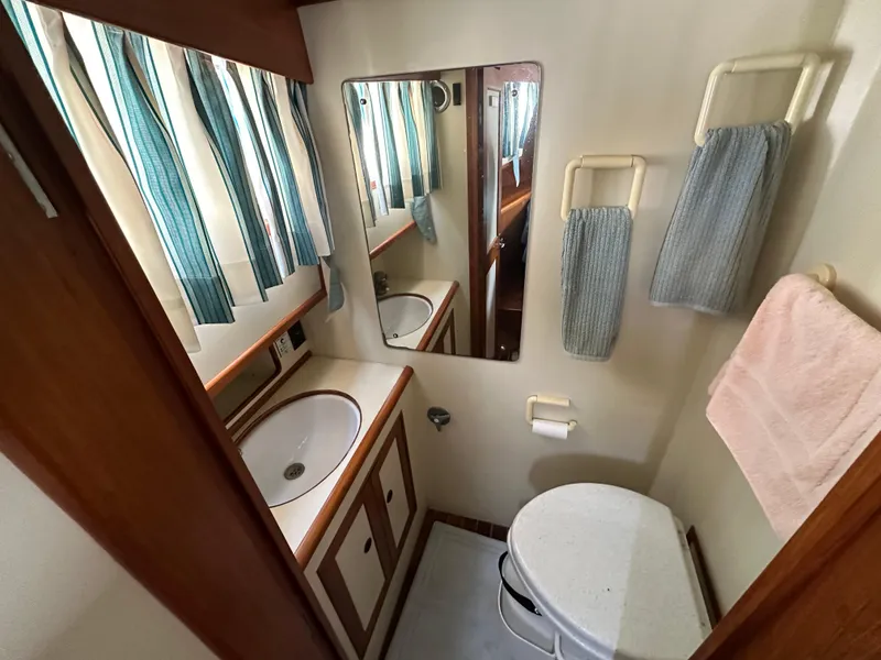 Slide: The Image of Bathroom interior of 1996 Island Gypsy 36 Aft Cabin with sink, mirror, and towels. - 26