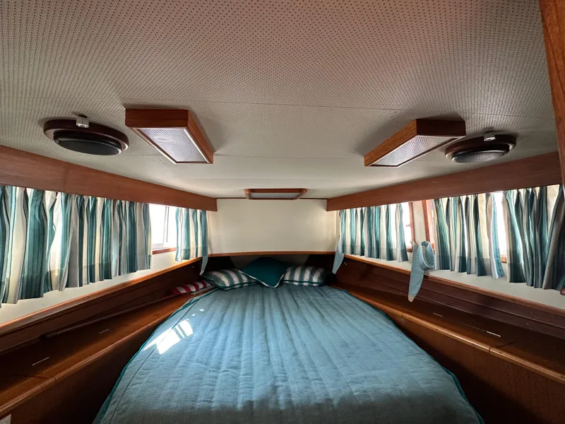 Slide: The Image of 1996 Island Gypsy 36 Aft Cabin interior with bed, striped curtains, and wooden accents. - 31
