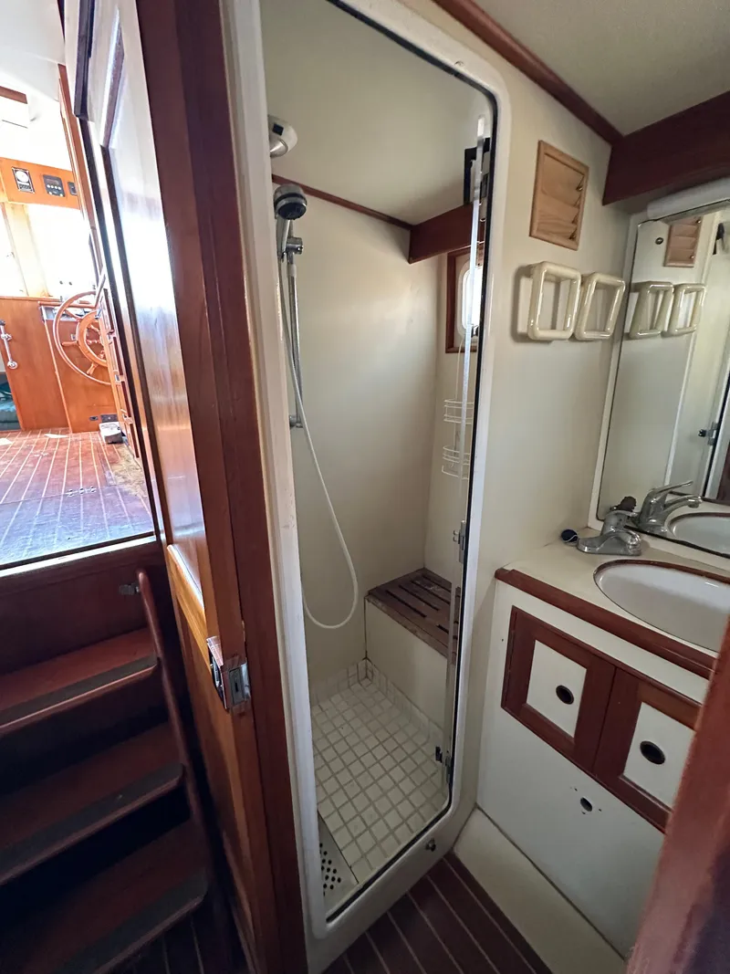Slide: The Image of 1996 Island Gypsy 36 Aft Cabin bathroom with shower, sink, and wooden accents. - 37
