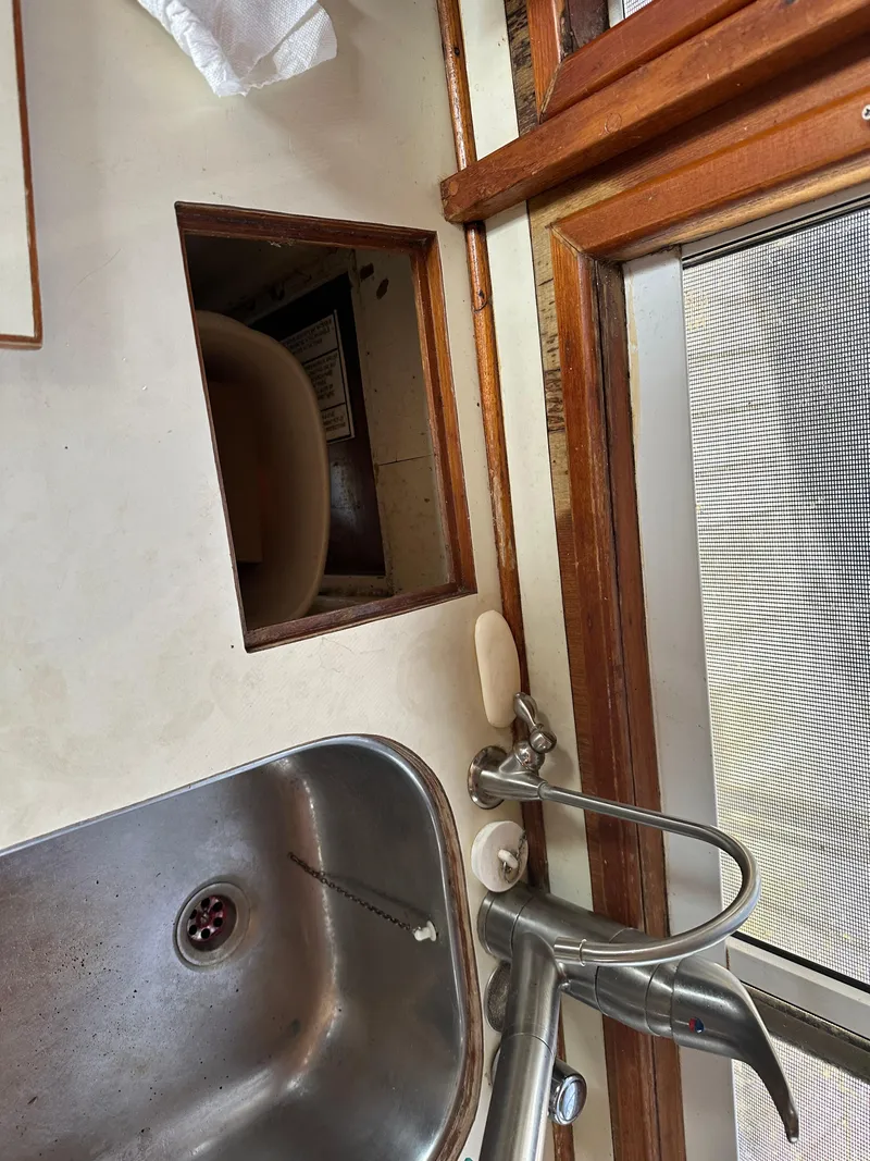 Slide: The Image of 1996 Island Gypsy 36 Aft Cabin kitchen sink with faucet and open storage compartment. - 40