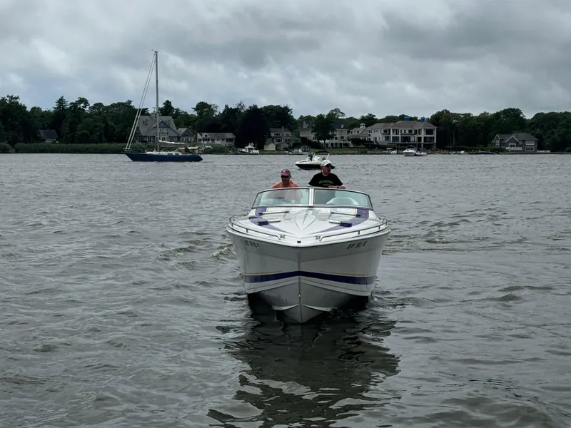 Slide: The Image of 2020 Formula 382 FASTech boat cruising on a lake with houses in the background. - 2