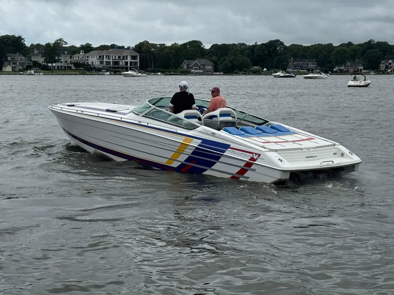 Slide: The Image of 2020 Formula 382 FASTech speedboat cruising on a lake with houses in the background. - 5