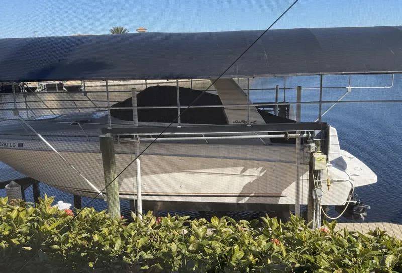 Slide: The Image of 1998 Sea Ray 310 Sundancer docked under a canopy, surrounded by greenery. - 2