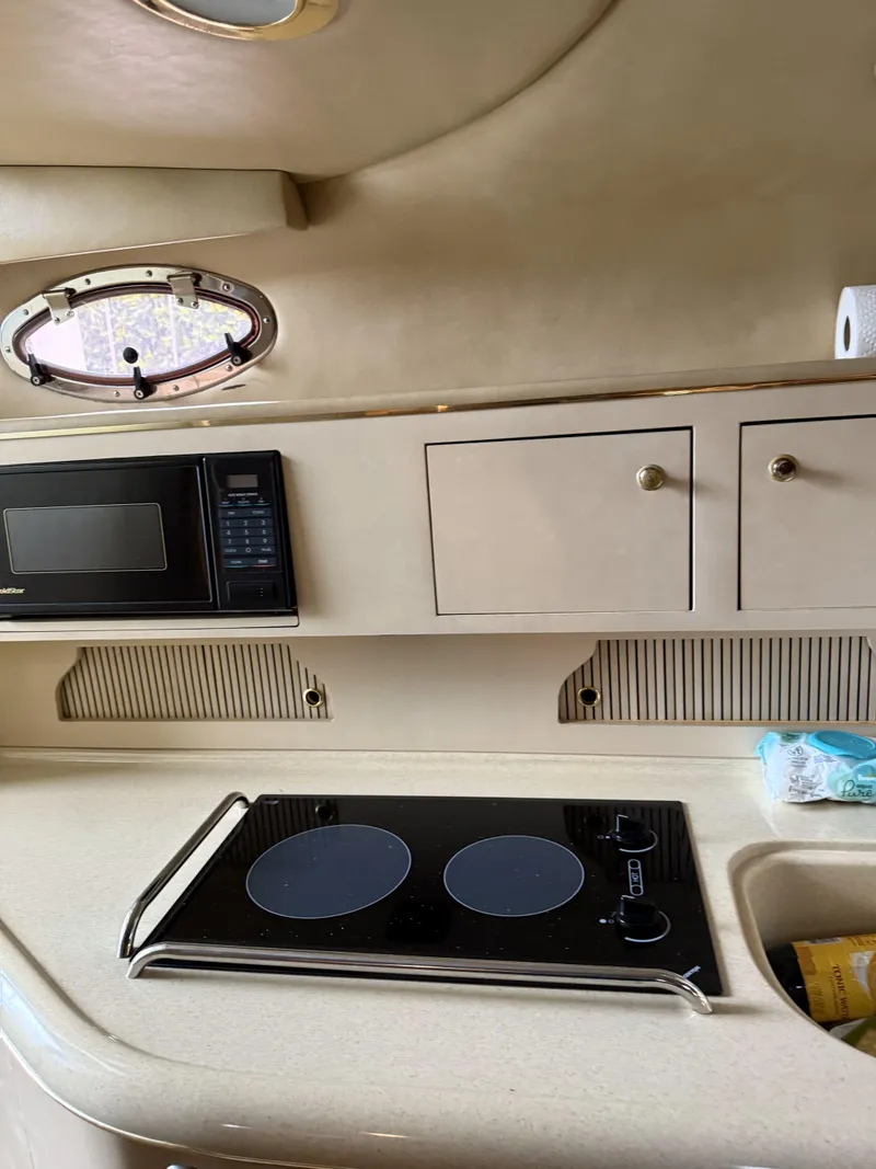 Slide: The Image of 1998 Sea Ray 310 Sundancer interior kitchen with stove, microwave, and storage cabinets. - 5