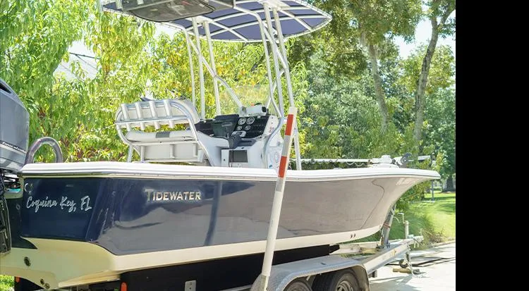 The Image of 2012 Tidewater 2200 Carolina Bay boat on trailer, parked outdoors with lush greenery. - 1