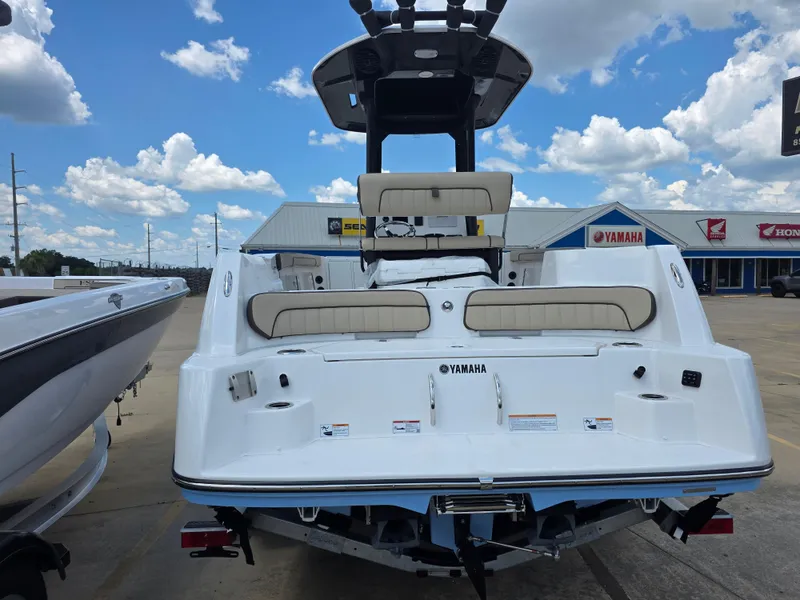 Slide: The Image of 2025 Yamaha Boats 222 FSH Sport E, rear view, parked at dealership under blue sky. - 14