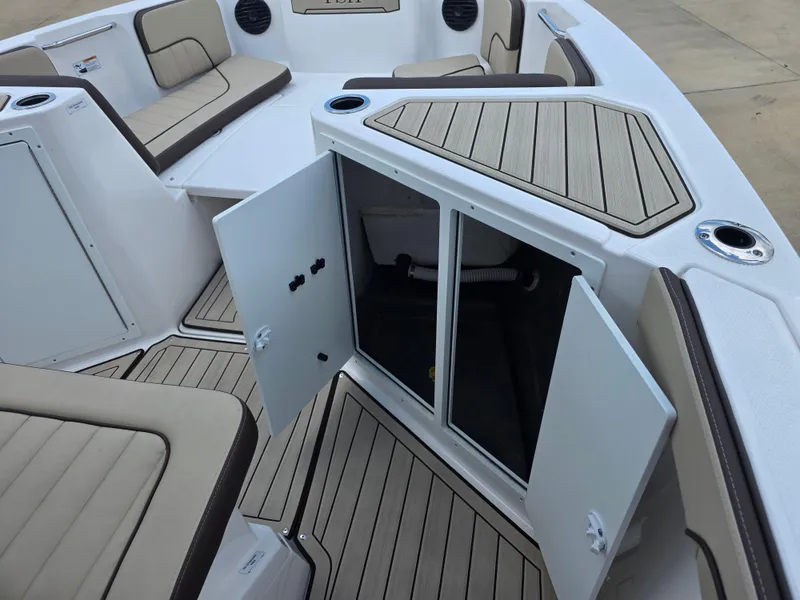 Slide: The Image of 2025 Yamaha Boats 222 FSH Sport E interior with open storage compartment and cushioned seating. - 5