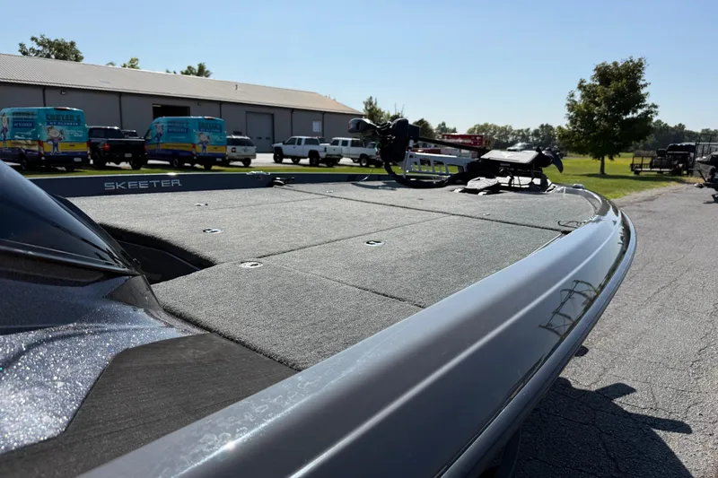 Slide: The Image of 2025 Skeeter ZXR21 boat deck, parked outdoors near vehicles and trees. - 14