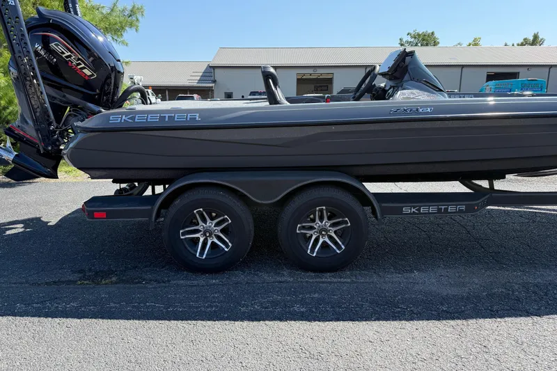 Slide: The Image of 2025 Skeeter ZXR21 boat on trailer, parked outdoors, featuring sleek design and powerful engine. - 19