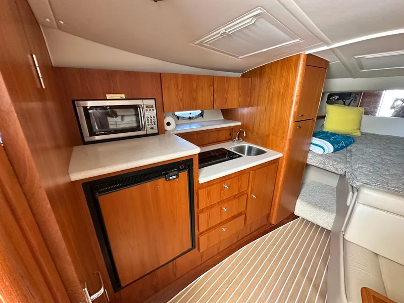 Slide: The Image of 2003 Tiara Yachts 3100 Open interior with kitchenette, microwave, and cozy sleeping area. - 29