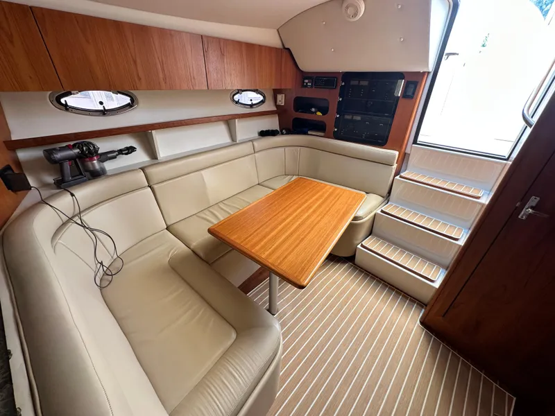 Slide: The Image of 2003 Tiara Yachts 3100 Open interior with beige seating and wooden table. - 30