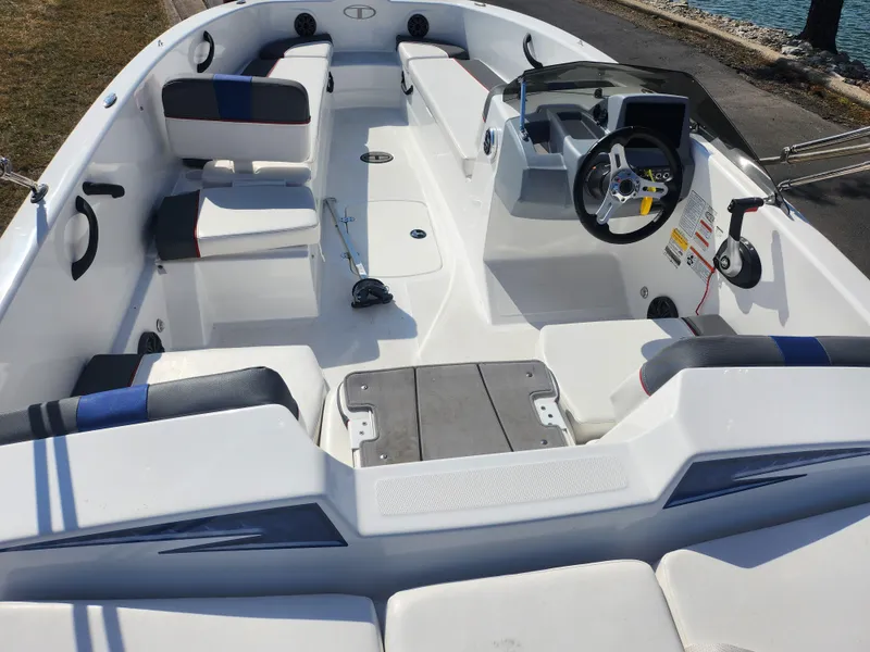 Slide: The Image of 2023 Tahoe T18 boat interior with seating, steering wheel, and dashboard near water. - 10