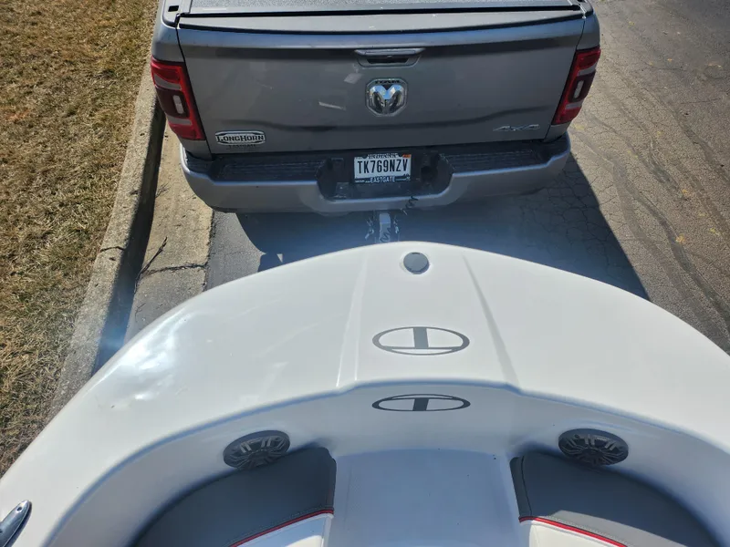 Slide: The Image of 2023 Tahoe T18 boat parked behind a gray pickup truck on a sunny day. - 15