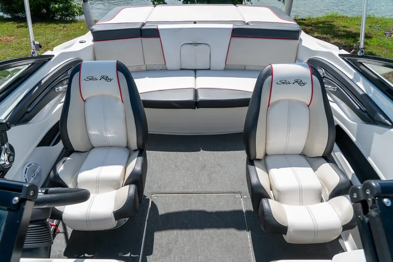 Slide: The Image of 2014 Sea Ray 205 Sport boat interior with white and black seating, near water. - 19