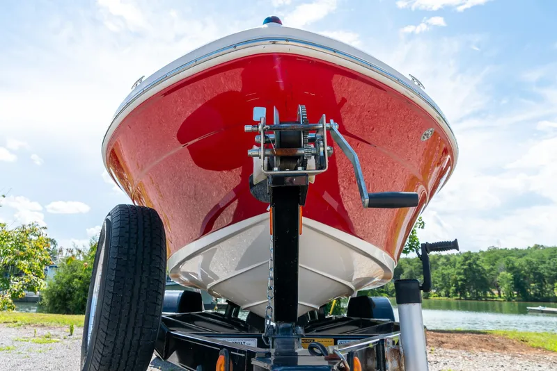 Slide: The Image of 2014 Sea Ray 205 Sport boat on trailer, red hull, lakeside background. - 24