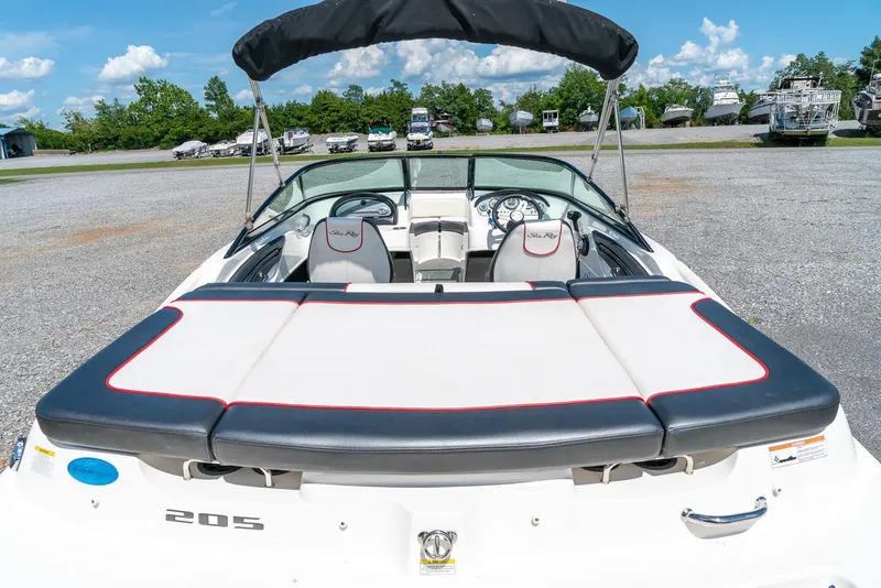 Slide: The Image of 2014 Sea Ray 205 Sport boat with sunpad, parked outdoors under blue sky. - 9
