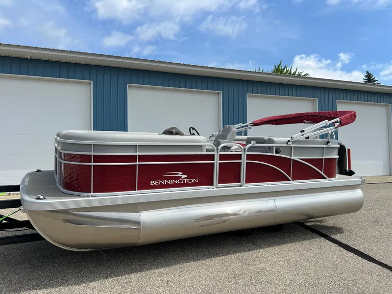 The Image of 2023 Bennington 20 SVSR pontoon boat with red and silver design, parked outdoors. - 0