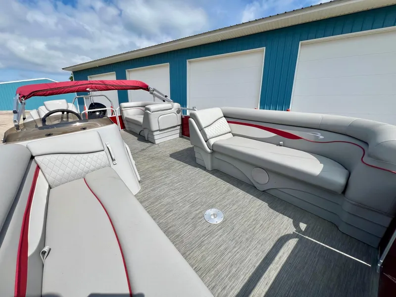 Slide: The Image of 2023 Bennington 20 SVSR pontoon boat with spacious seating and red accents, docked near blue building. - 15