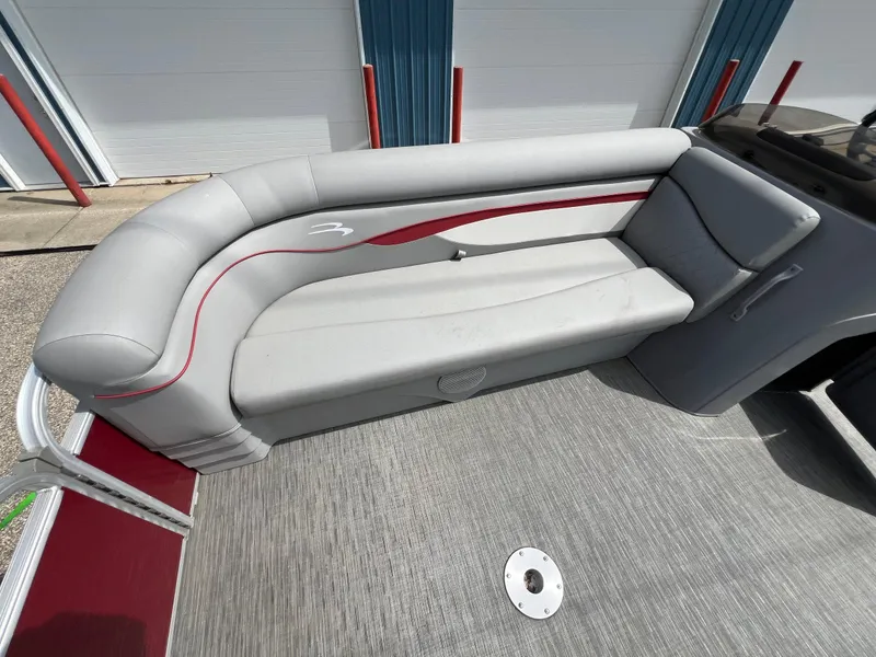 Slide: The Image of 2023 Bennington 20 SVSR pontoon boat with gray and red seating, docked near a building. - 16