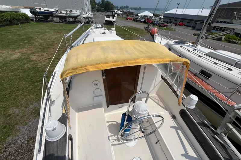 Slide: The Image of 1980 Pearson 30 sailboat with yellow canopy in harbor. - 13