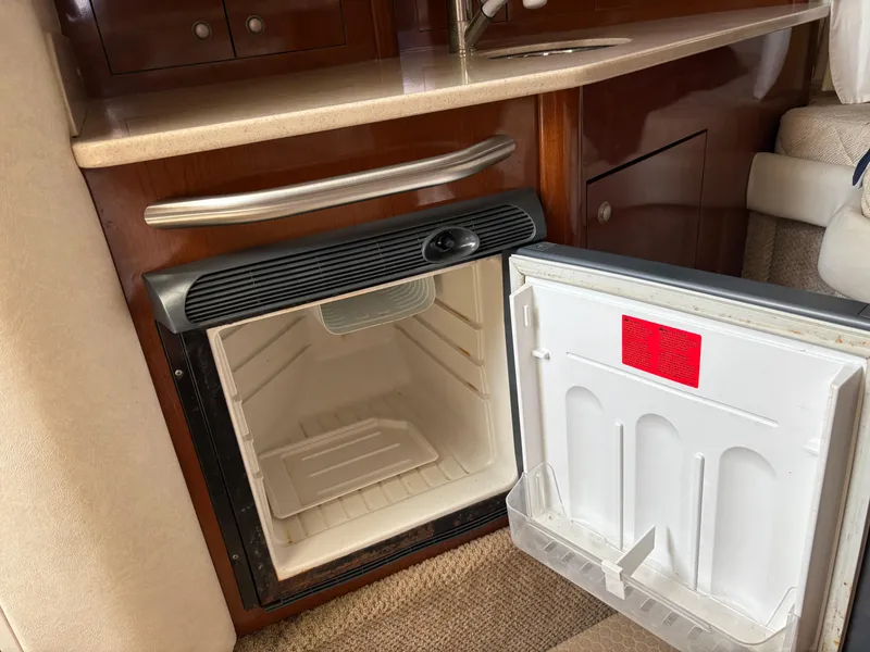 Slide: The Image of Open mini fridge inside 2008 Sea Ray 290 Amberjack boat cabin, featuring wood cabinetry and countertop. - 17