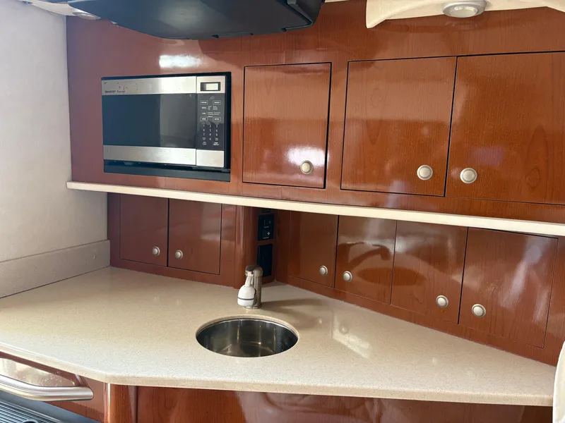 Slide: The Image of 2008 Sea Ray 290 Amberjack kitchen with microwave, sink, and wooden cabinets. - 18