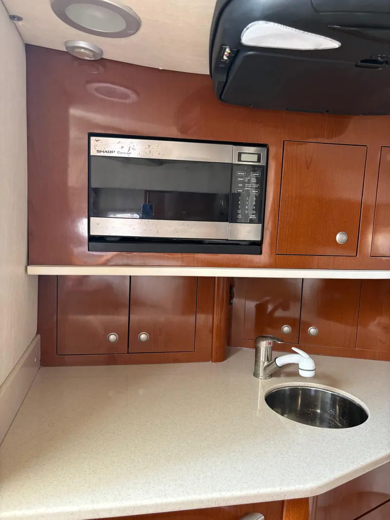 Slide: The Image of 2008 Sea Ray 290 Amberjack kitchen with microwave, sink, and wooden cabinetry. - 19