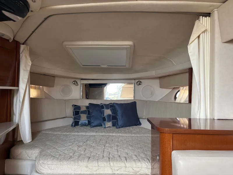 Slide: The Image of 2008 Sea Ray 290 Amberjack cabin interior with bed, pillows, and wooden accents. - 25