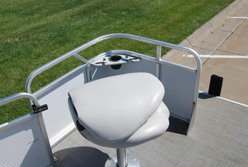 Slide: The Image of 2016 Apex Marine QUEST 7516 boat seat with railing, cup holder, and grassy background. - 12
