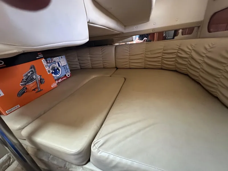 Slide: The Image of 2004 Rinker Fiesta Vee 312 cabin interior with beige seating and a boxed vacuum cleaner. - 11