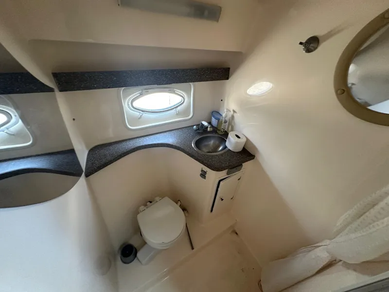 Slide: The Image of 2004 Rinker Fiesta Vee 312 bathroom with sink, toilet, and porthole window. - 12