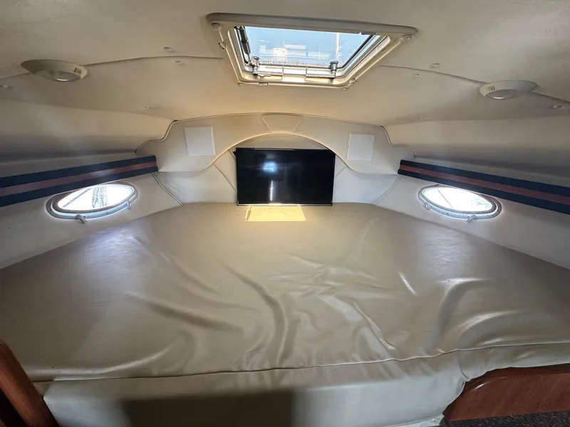 Slide: The Image of 2004 Rinker Fiesta Vee 312 cabin interior with bed, portholes, and ceiling hatch. - 18