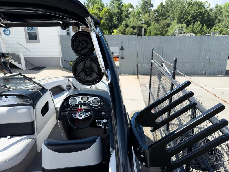 Slide: The Image of 2006 Malibu 23 VLX boat interior with speakers and steering wheel, parked near a fence. - 12