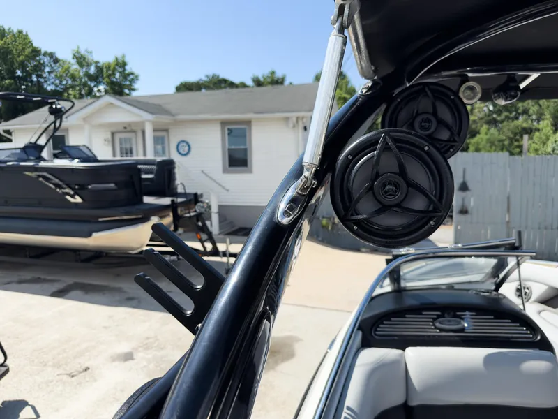 Slide: The Image of 2006 Malibu 23 VLX boat with speakers and wakeboard rack, parked near a house. - 13