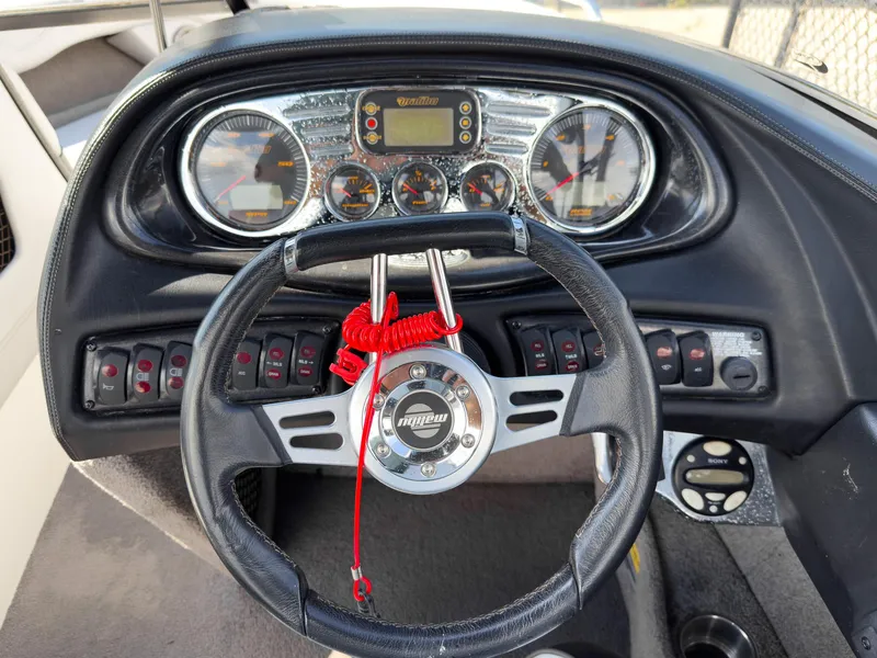 Slide: The Image of Dashboard of a 2006 Malibu 23 VLX boat with steering wheel and gauges. - 14