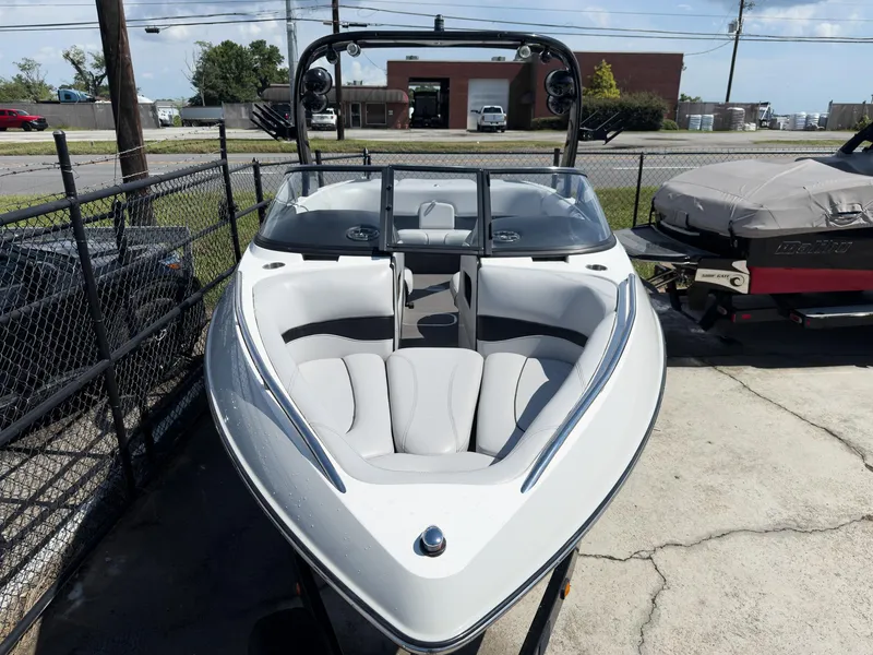 Slide: The Image of 2006 Malibu 23 VLX boat with sleek design and spacious seating, parked outdoors. - 2
