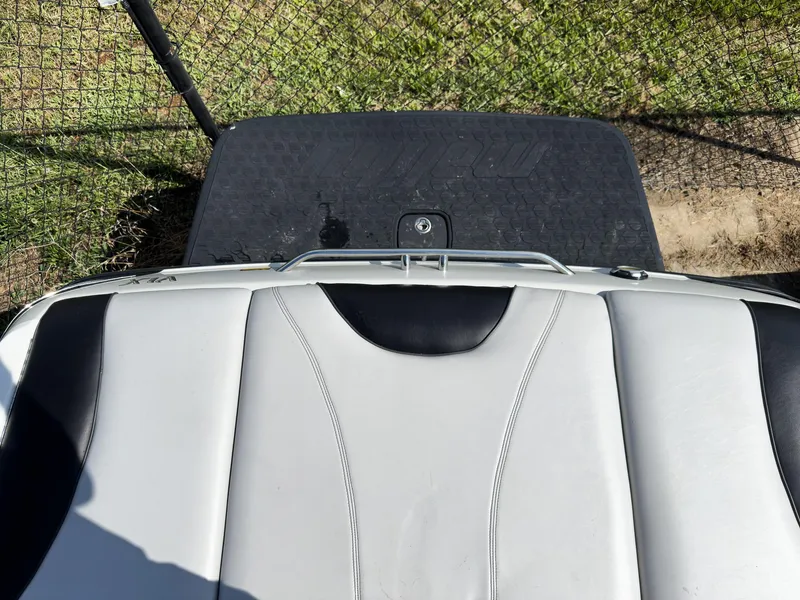 Slide: The Image of 2006 Malibu 23 VLX boat interior with white and black upholstery, near a fence. - 20