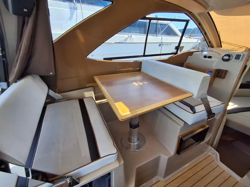 Slide: The Image of 2017 Cutwater C24 interior with dining area and seating, featuring wood table and cushioned benches. - 10