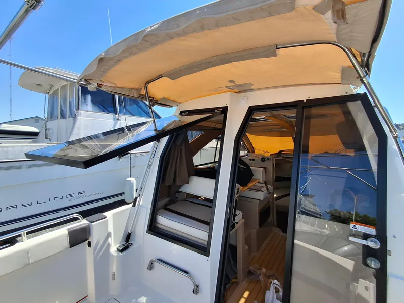 Slide: The Image of 2017 Cutwater C24 boat interior with open doors and canopy, docked beside another vessel. - 12